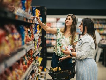 Two women grocery shopping in a supermarket.