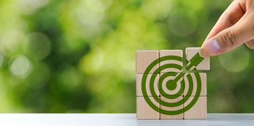 Hand placing wooden block completing a target with arrow symbol.