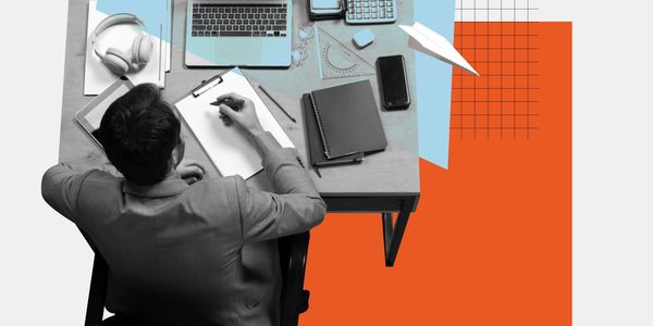 Man working at a desk with laptop, notebook, and office supplies in a creative workspace.
