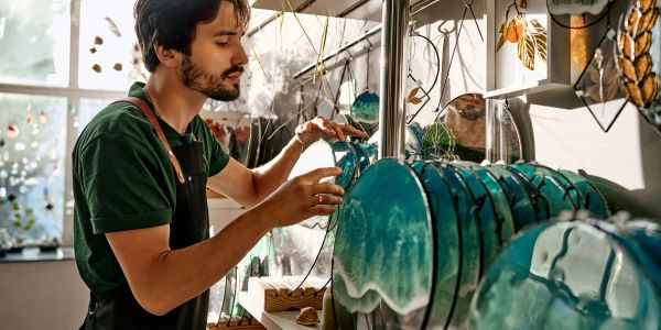 Hombre trabajando con arte de vidrio en un taller.