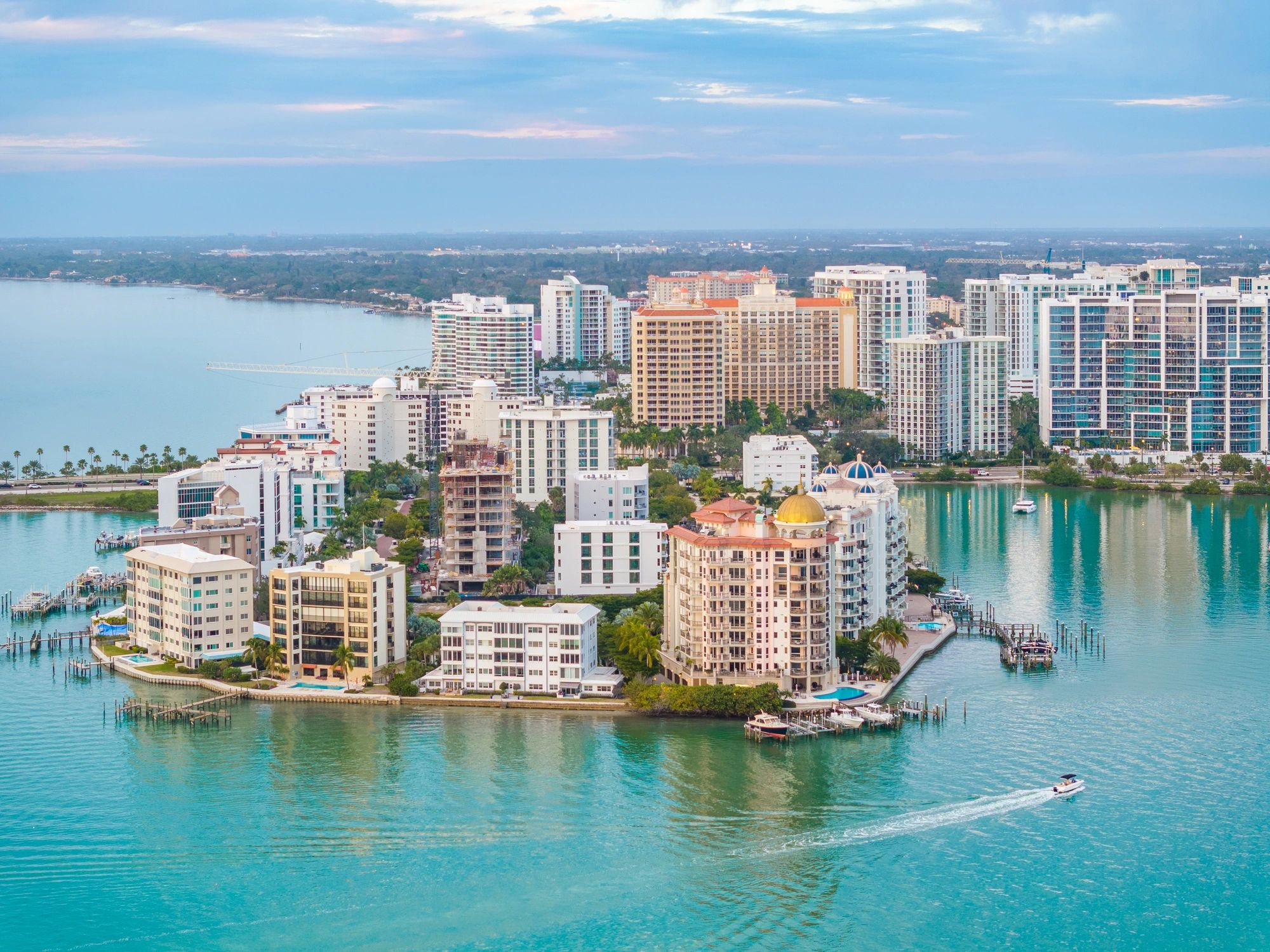 Aerial view of waterfront cityscape with boats and high-rise buildings.