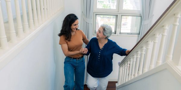 Young woman helping elderly woman up the stairs.