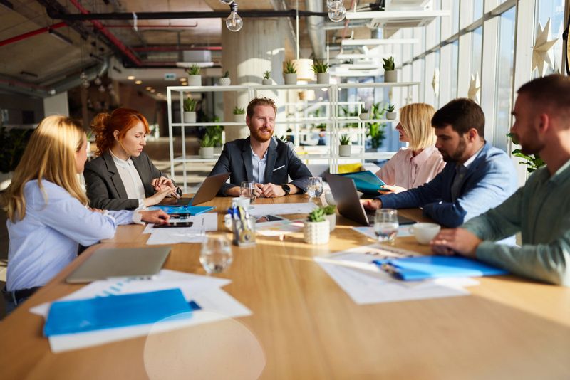 Happy male manager talking to his team during a meeting in a modern office.
