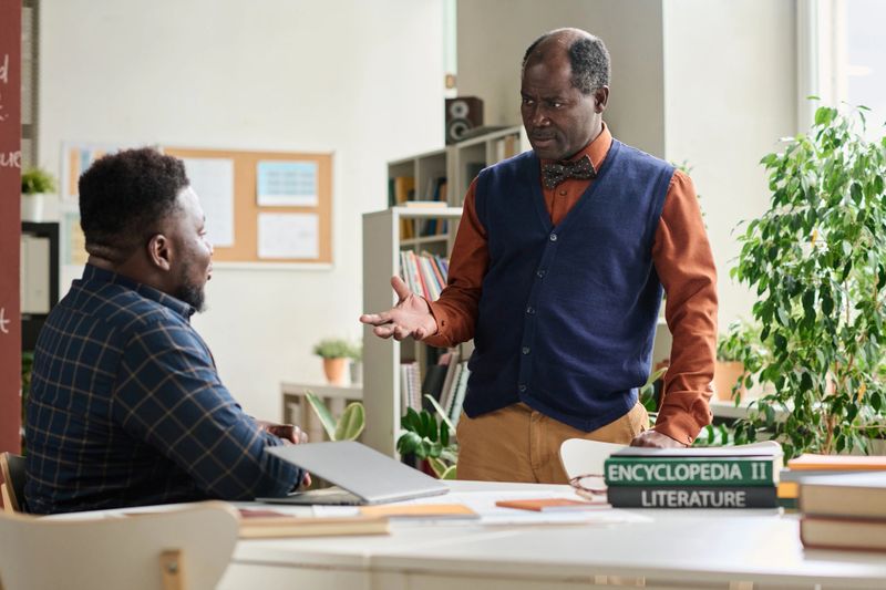 Portrait of Black senior professor consulting student during one on one meeting in school classroom