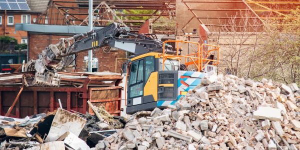 Excavator clearing rubble at a demolition site.