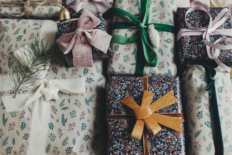 Merry Christmas! Stylish christmas gifts in festive wrapping paper, bows, ribbons, vintage ornaments on wooden table top view. Atmospheric winter holidays preparation