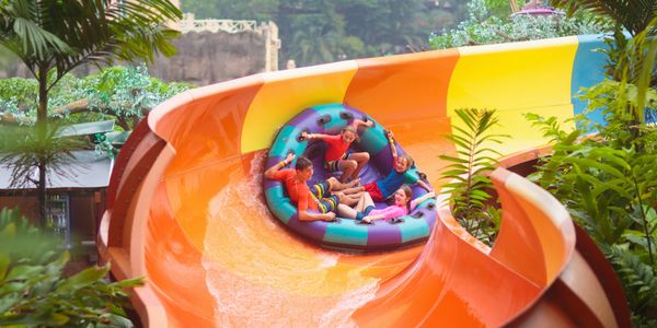Four people enjoying a colorful water slide on a large raft.