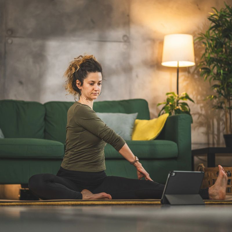 Woman practice yoga on mat in living room at home use digital tablet for online class training