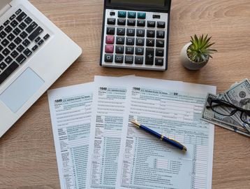 Work station set up with 1040 documents with money and a calculator 