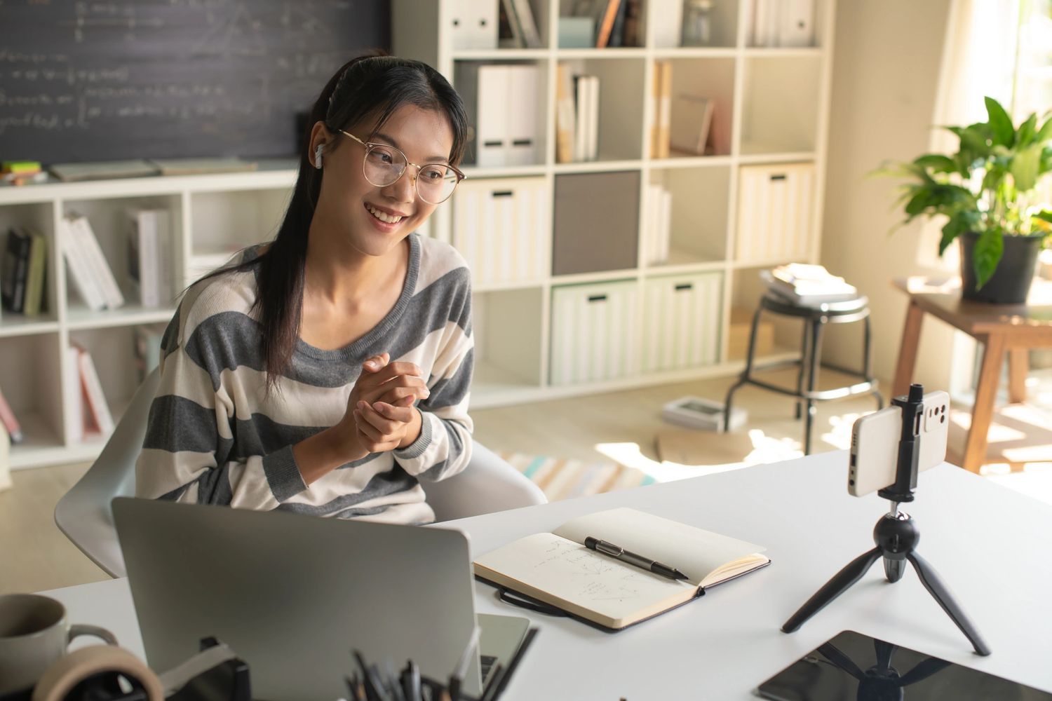Young woman video chatting at home with laptop and smartphone.