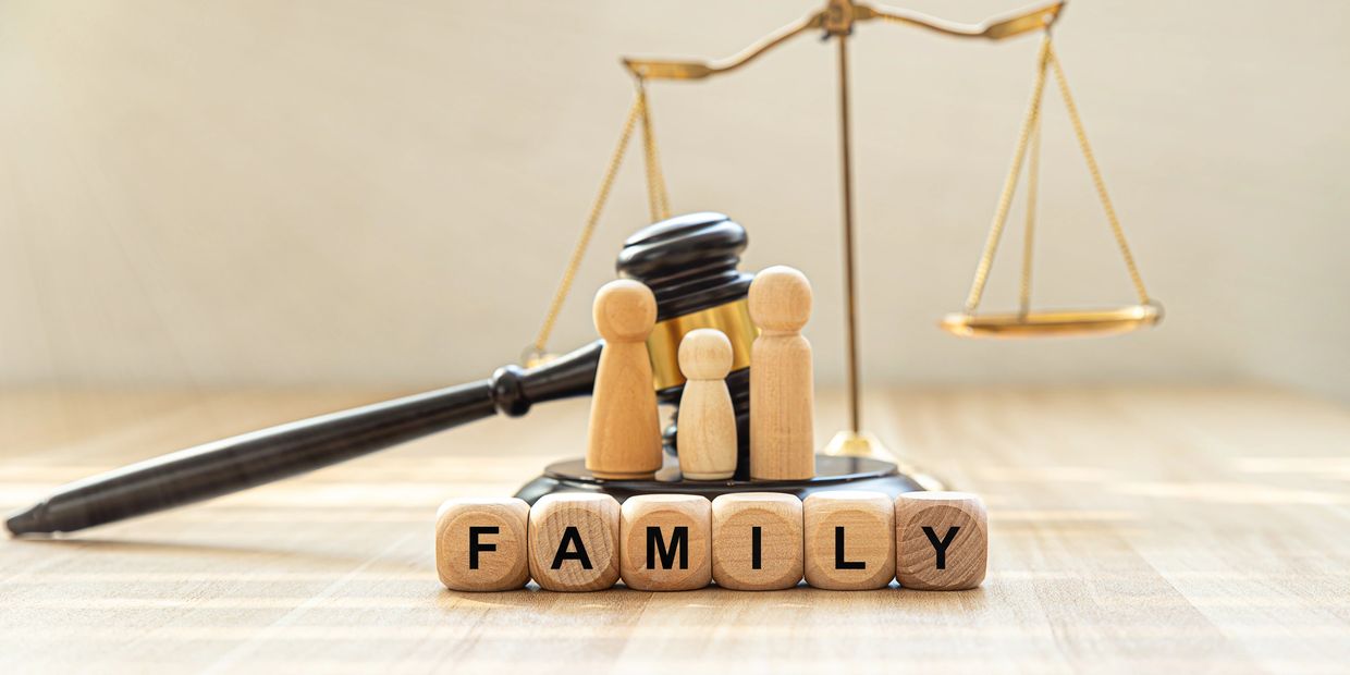 Wooden blocks spelling FAMILY with legal gavel and scales in background.