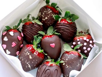 Box of chocolate-covered strawberries with decorative toppings.