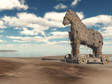 Caballo de Troya de madera en la playa bajo un cielo azul.