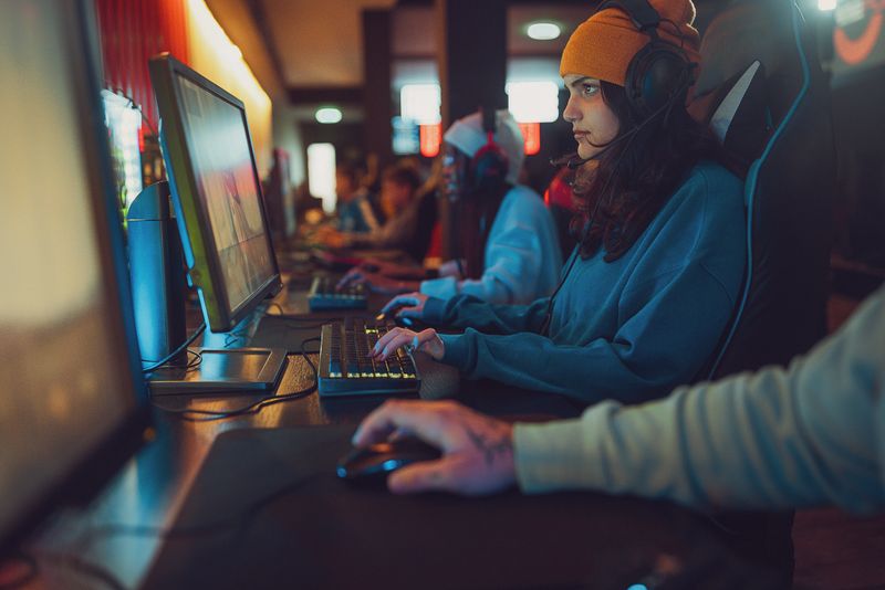 Multiracial group of people, professional cybersport gamers playing video games on desktop computers together in gaming club.