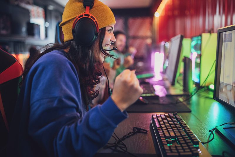Multiracial group of people, professional cybersport gamers playing video games on desktop computers together in gaming club.