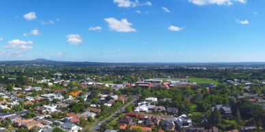 A suburban neighborhood under a blue sky with scattered clouds.