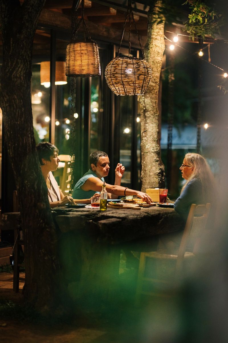Group of mature female friends smiling and talking together while eating pizza outside on a restaurant patio in the evening