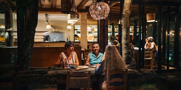 Three women dining outdoors at a rustic restaurant in the evening.
