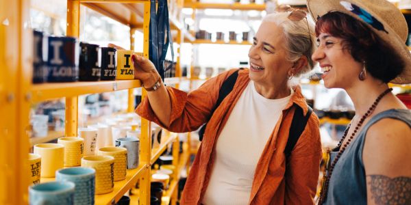 Two women shopping for mugs in a store.