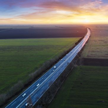 A highway cutting through vast green fields at sunset.