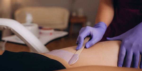 Applying wax on a person's leg for hair removal.