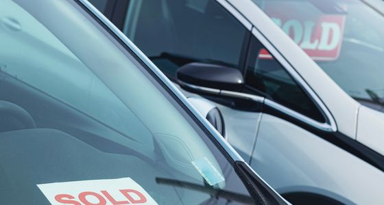 Blurred image of cars with two people in the background in a showroom.