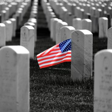 American flag placed at a grave in a military cemetery.