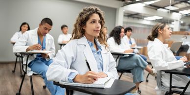 Medical students attentively taking notes in a classroom.