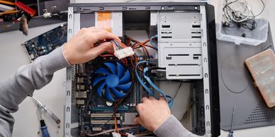 Technician repairing a desktop computer and connecting internal components.