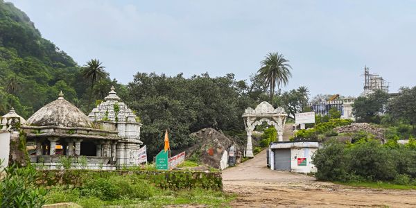 Entrance to a temple complex with greenery and hills.