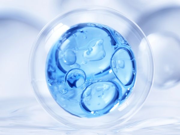 Close-up of a translucent blue bubble with smaller bubbles inside, surrounded by blurred circular shapes.