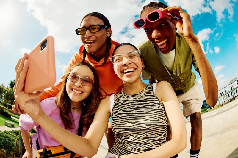 Carefree Generation Z Friends using smartphone for social media.