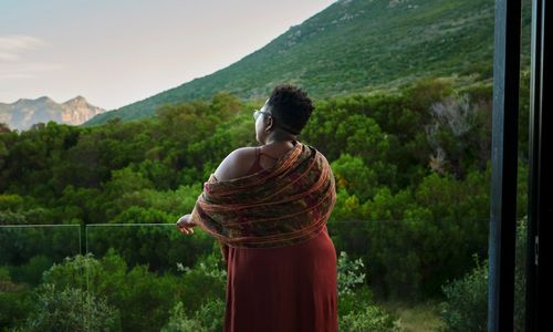 Person enjoying a scenic mountain and forest view from a balcony.