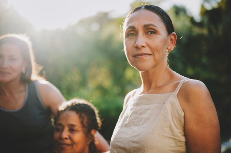 Portrait of a mature woman standing outdoors with a diverse group of other women during a wellness retreat in summer