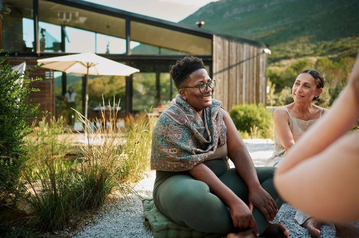 Two women sitting outdoors, enjoying a sunny day and conversation.