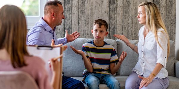 Parents arguing with a confused child during family therapy session.