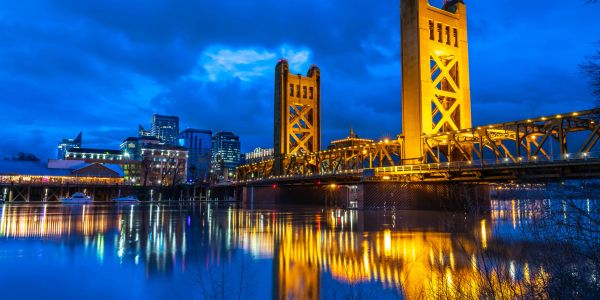 Golden bridge illuminated at night over calm water.