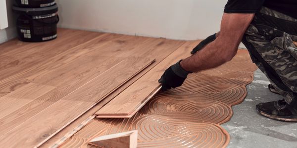 Worker installing wooden flooring with adhesive.