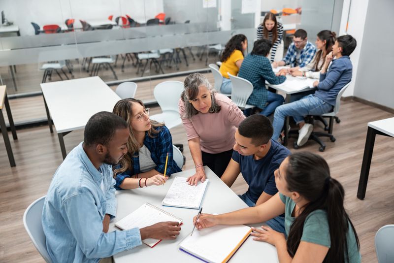 Teacher in class explaining something to a group of Latin American students at a community college - education concepts
