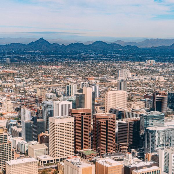 A sprawling cityscape with mountains in the background under a blue sky.