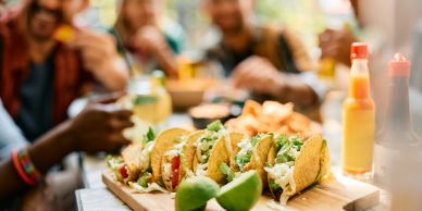 Tacos served on a wooden board with lime wedges.