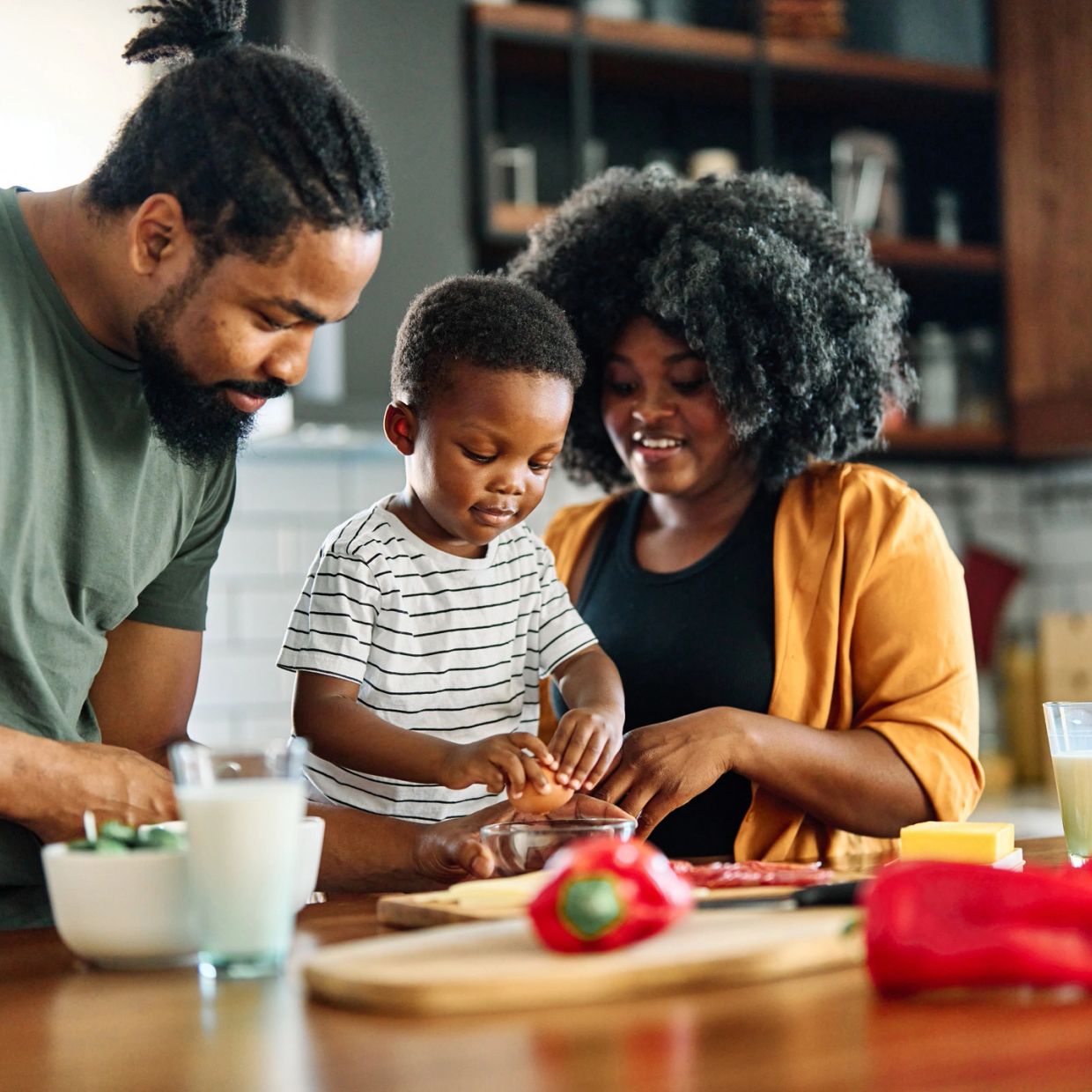 Family cooking together with a child cracking an egg.