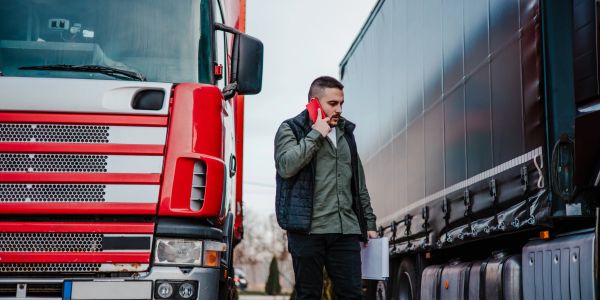Man talking on phone between two trucks.