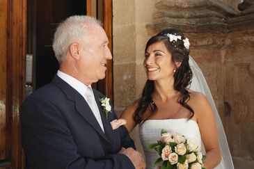 Bride and older man sharing a joyful moment at a wedding.