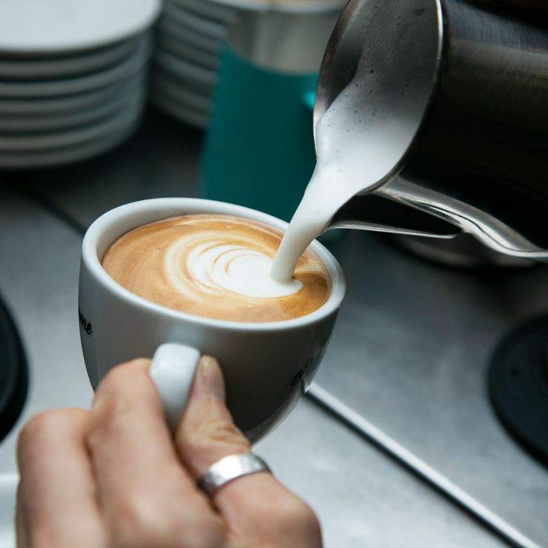 Professional barista working with a coffee machine and preparing hot drinks with coffee and milk..