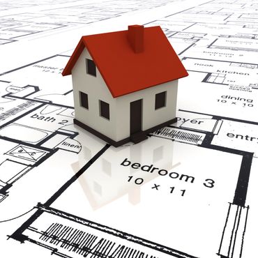 A small house model placed on architectural blueprints.