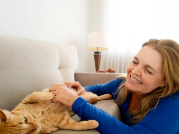 Woman playing with her happy cat on the couch.
