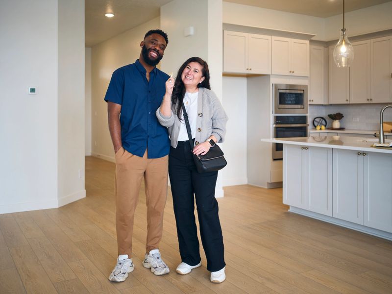 New home buying couple celebrating in their new home.