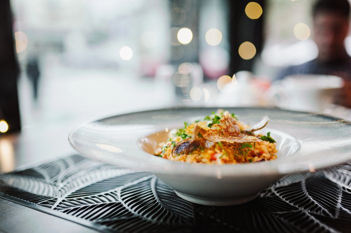 Gourmet risotto dish garnished with herbs in an elegant white bowl.