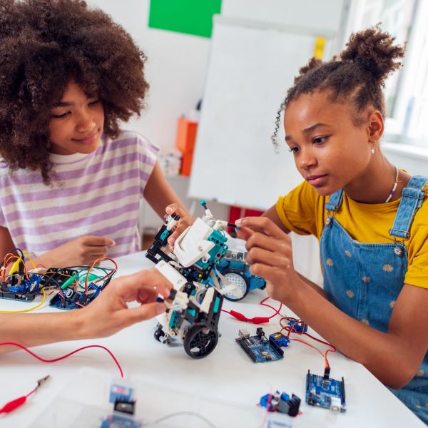 Two girls building robots with electronic components.